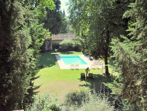 A swimming pool surrounded by trees, with a stone building in the background. - Tuscan Haven With Pool (San Casciano in Val di Pesa)