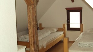 A small, attic-style bedroom with two wooden bunk beds, a window, and a sloped ceiling. - Detached House With Sauna Near Ski Lifts (Winterberg)