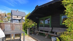 A wooden cabin with a porch, a metal table, and benches. - Detached House With Sauna Near Ski Lifts (Winterberg)