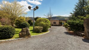 A gravel driveway leading to a building with a stone facade, surrounded by well-maintained shrubbery and trees. - Chic Vacation Home near Forest in Sebnitz Germany (Sebnitz)