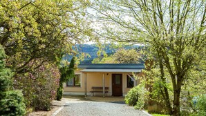 A building with a covered porch, a bench, and a gravel path leading to it. - Chic Vacation Home near Forest in Sebnitz Germany (Sebnitz)