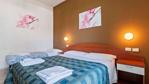 Une chambre d’hôtel avec un grand lit, deux tables de chevet et deux lampes fixées au mur.