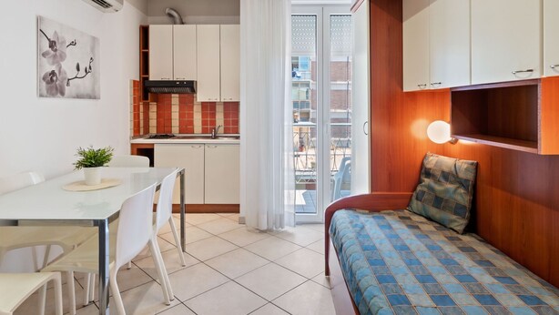 Un espace de vie compact comprenant une kitchenette, un coin repas et une chambre.