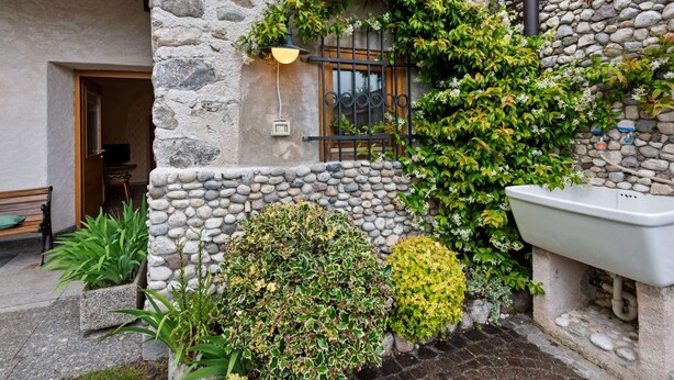 A stone building with a window, a sink, and various plants.