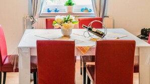 A dining area with a table set for two, a vase of flowers, and a wine bottle on a coaster. - Splendid Apartment near Ski Area in Medebach (Medebach)
