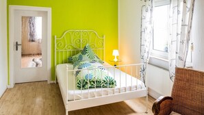 A room with a bed, a wicker chair, a window with curtains, and a door. - Splendid Apartment near Ski Area in Medebach (Medebach)