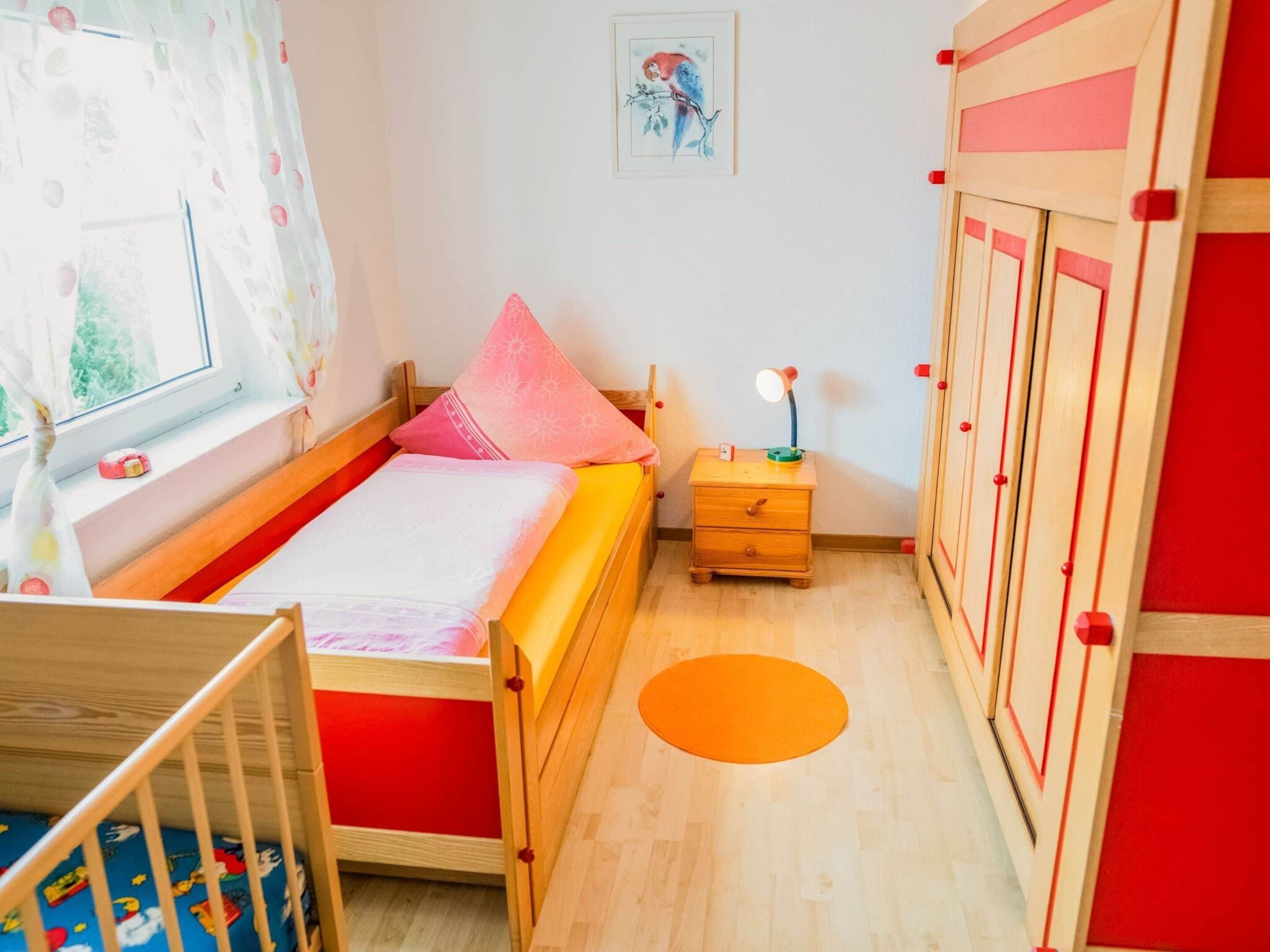 A child's bedroom with a bed, nightstand, and wardrobe.