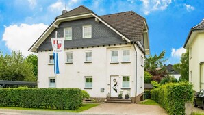 A two-story building with a white facade and a dark roof. There is a flag with a coat of arms on the left side of the building. - Splendid Apartment near Ski Area in Medebach (Medebach)