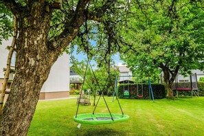 Un arbre avec une balançoire dans une cour gazonnée.