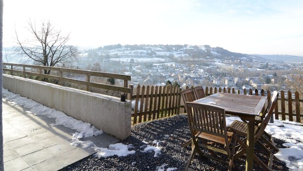 An outdoor seating area with a view of a town and hills in the background. - Panoramic Retreat in Malmedy (Malmedy)