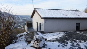 A small, single-story building with a snow-covered roof, a visible number '15', and a view of a town in the background. - Panoramic Retreat in Malmedy (Malmedy)