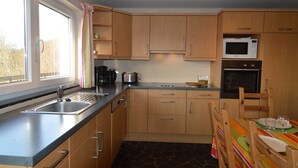 A modern kitchen with wooden cabinets, a stainless steel sink, a microwave, and an oven. - Panoramic Retreat in Malmedy (Malmedy)