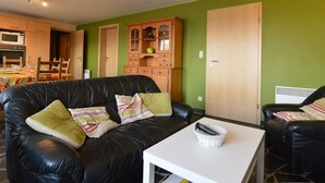 A living room with a black leather sofa, a white coffee table, and a wooden cabinet. - Panoramic Retreat in Malmedy (Malmedy)