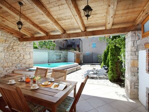 A covered outdoor dining area with a pool, stone walls, and wooden furniture. - Luxurious Holiday Home in Barban With Private Pool (Barban)