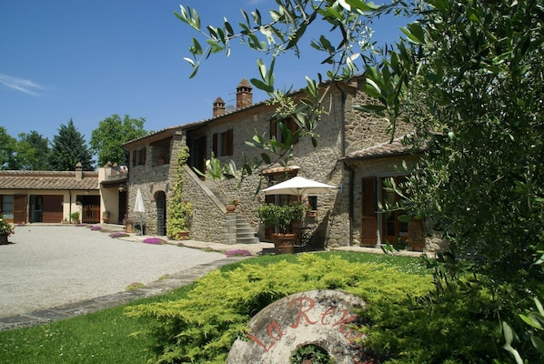 A stone building with a courtyard, outdoor seating, and a large rock with text.