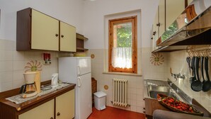 Una cocina compacta con refrigerador, lavamanos y armarios de madera.
