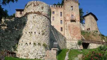 A historic stone castle with a large round tower and a rectangular building with battlements.