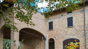 Ein Innenhof mit einem Backsteinbogen, Steinmauern und einer grünen Tür.