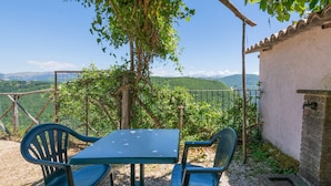 A table and chairs under a tree with a view of mountains. - Holiday Home in Sellano With Pool & Views (Sellano)