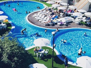 A large outdoor swimming pool with multiple lanes, surrounded by lounge chairs and umbrellas. - Relaxing Resort Apartment (Comacchio)