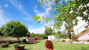 A backyard with a trampoline, red lounge chairs, a potted plant, and a statue of a rabbit. - Comfortable and Quiet Apartment in Istria With Privacy (Barban)