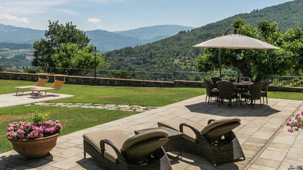 An outdoor patio with lounge chairs, a dining table, and a pergola with an umbrella. - Scenic Stay in Poppi With Pool (Poppi)