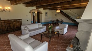 A spacious living area with a high wooden ceiling, a brick floor, a sofa, a coffee table, and a fireplace. - Scenic Stay in Poppi With Pool (Poppi)