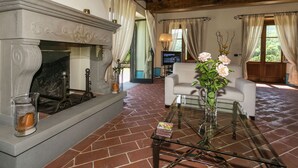A living room with a fireplace, a glass coffee table, and a TV in the background. - Scenic Stay in Poppi With Pool (Poppi)
