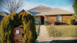 A single-story brick house with a sloped roof, a front entrance, and a mailbox.