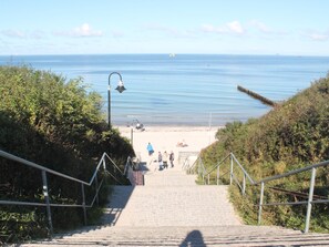 A staircase leading to a beach with a clear view of the sea and a distant ship. - Ferienwohnung, Nienhagen (Nienhagen)