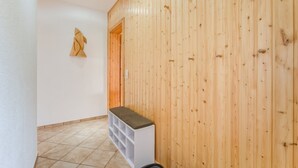A hallway with wooden paneling, a white bench, and a tiled floor. - Idyllic Apartment in Kühlungsborn Germany near Forest (Kuehlungsborn)