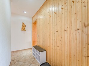 Un couloir aux murs lambrissés, avec un banc blanc et un sol carrelé.