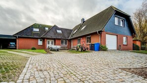 A two-story house with a paved driveway and a garage. - Idyllic Apartment in Kühlungsborn Germany near Forest (Kuehlungsborn)