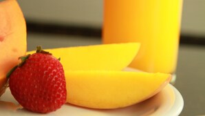 Un plato con mango en rodajas y una fresa.