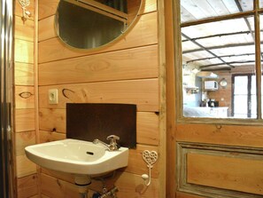 A wooden bathroom with a white sink, a mirror, and a heart-shaped towel ring.