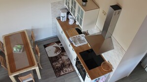 A compact kitchen with a dining area, including a table, chairs, and a small cabinet with a potted plant. - Farmhouse Near Baltic Sea Kuhlungsborn (Kroepelin)