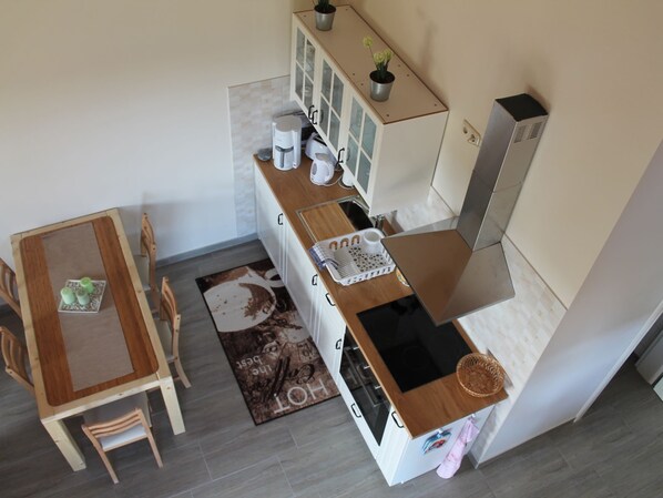 Cocina compacta con zona de comedor, que incluye una mesa, sillas y un mueble pequeño con una planta en maceta.
