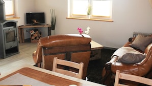 Un salon chaleureux avec une cheminée, un canapé en cuir, une table en bois et un téléviseur.