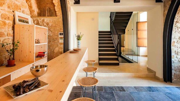 A modern interior with a stone wall, wooden bar, and a staircase leading to a lower level. - Belvilla by OYO Corte Dorata (Scicli)