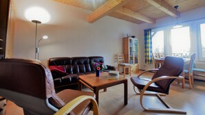 Un salon avec un plafond en bois, un canapé en cuir noir, une table basse en bois et un fauteuil à bascule.