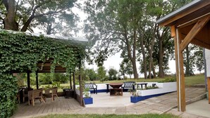 Un espace extérieur aménagé en terrasse, doté d’une pergola recouverte de verdure, de mobilier d’extérieur et d’un foyer.