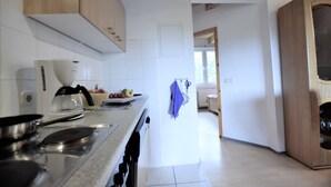 A modern kitchen with wooden cabinets, a stove, and a window. - Spacious Apartment in Boddin near Baltic Sea (Walkendorf)