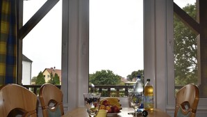 Une table à manger avec des chaises, un saladier, des assiettes, un verre et des bouteilles.