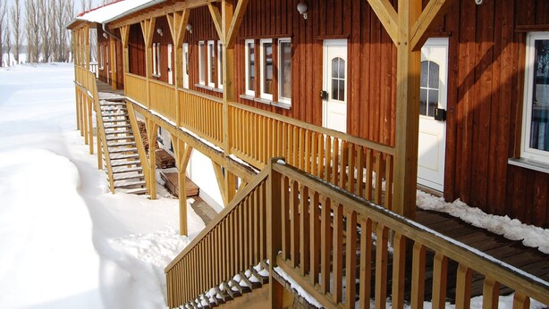 Une cabane en bois dotée d’un porche couvert et d’un escalier menant à l’entrée.
