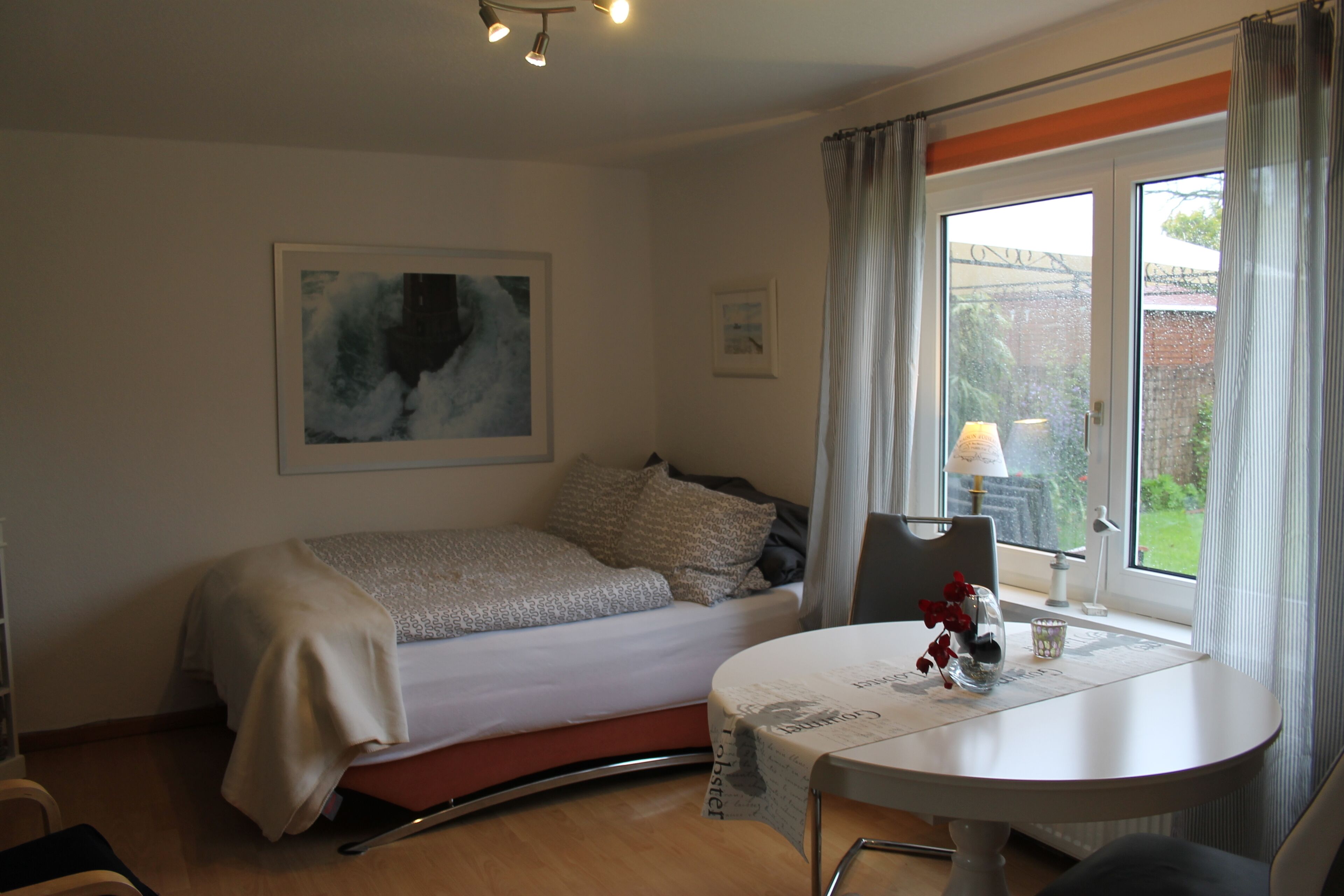 Un dormitorio con una cama, una mesita de noche con lámpara y una ventana con cortinas.