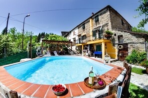 Ein Swimmingpool mit einer gefliesten Kante, einer Holzterrasse und einem Tisch mit Flasche und Glas.
