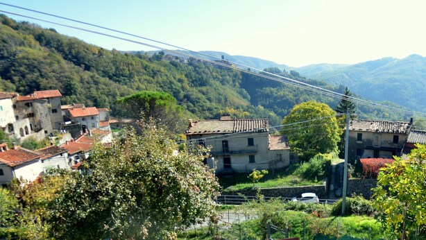 A rural village with traditional buildings, a narrow road, and a mountain backdrop. - Castelvecchio Family Retreat (San Marcello Piteglio)