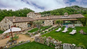 A stone building with a tiled roof, a swimming pool, and a grassy lawn with lounge chairs. - Villa Solace - Comfort Charm (Guardea)