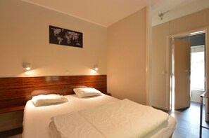 A hotel room with two beds, a wooden headboard, a wall-mounted light, and a door leading to a balcony. - Holiday Home in Marcourt With Garden (Rendeux)
