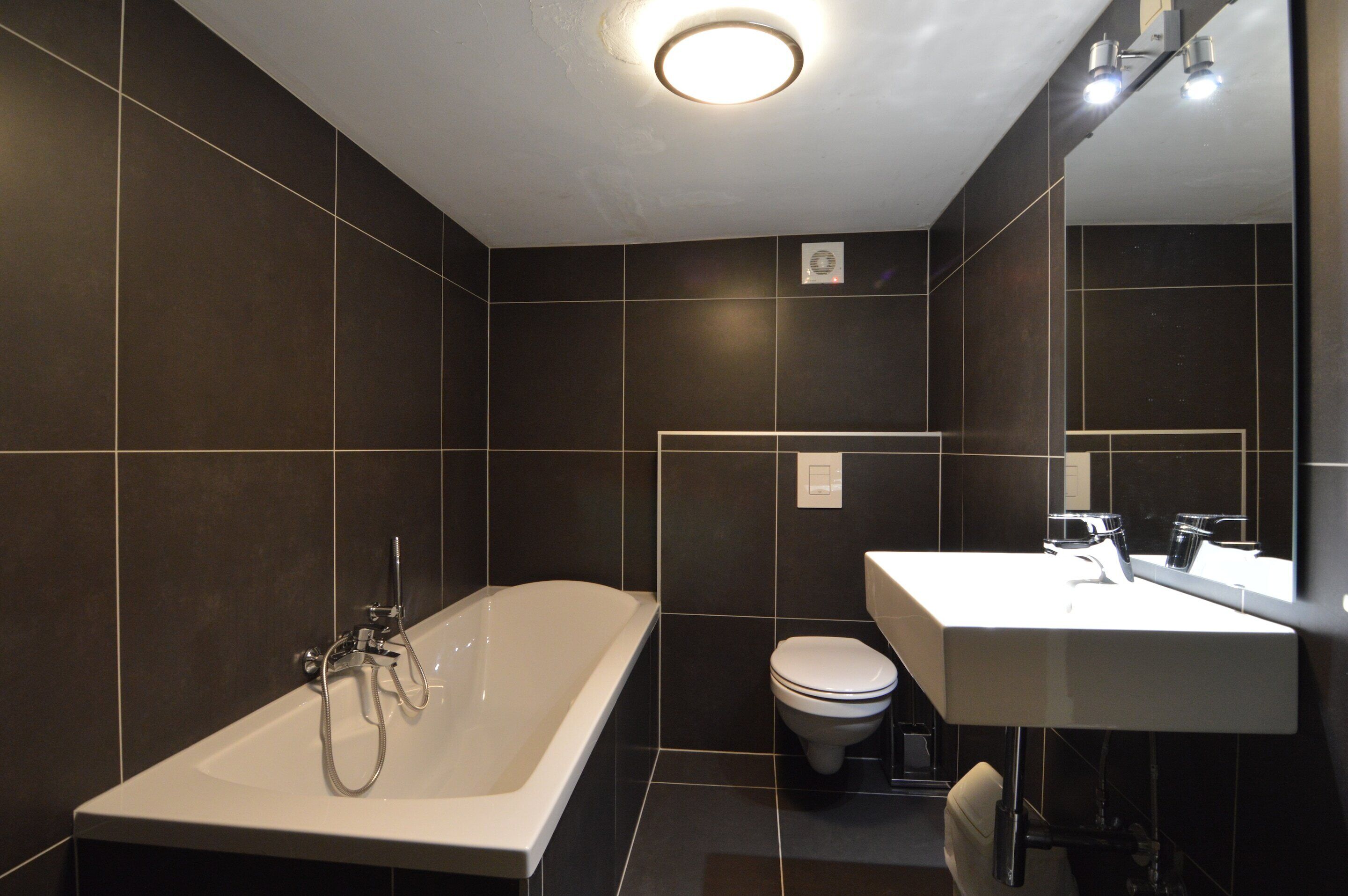A modern bathroom with a bathtub, toilet, and sink.